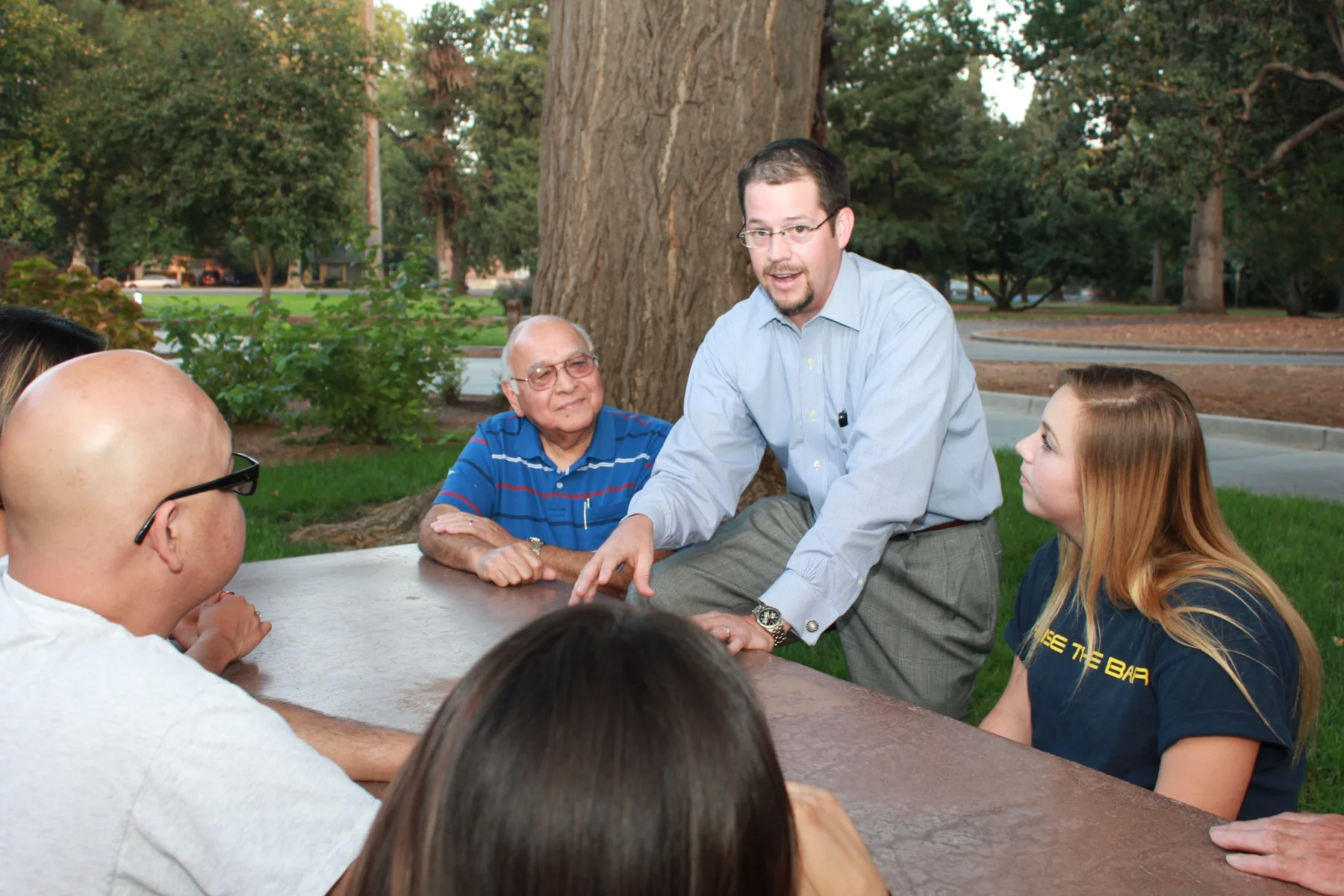 Randall Stone engaged in discussion with community members around an outdoor table